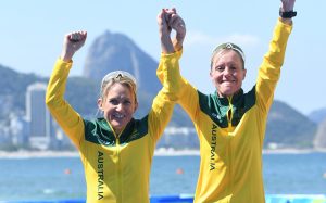 An image of Katie Kelly and Michellie Jones smiling while holding each other's hands