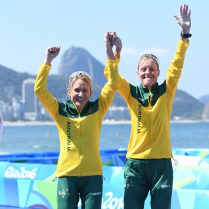 An image of Katie Kelly and Michellie Jones smiling while holding each other's hands