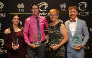 An image of four para-cyclists in an award ceremony, holding their awards and smiling