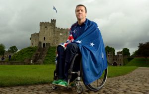 Male Paralympian Greg Smith in a wheelchair draped in the Australian flag