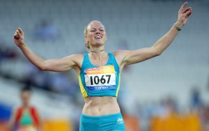 Australian Paralympian Katrina Webb crossing the finish line with her arms raised above her head.