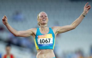 Australian Paralympian Katrina Webb crossing the finish line with her arms raised above her head.