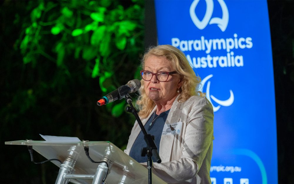 Paralympics Australia CEO Lynne Anderson standing behind a lecturn speaking into a microphone