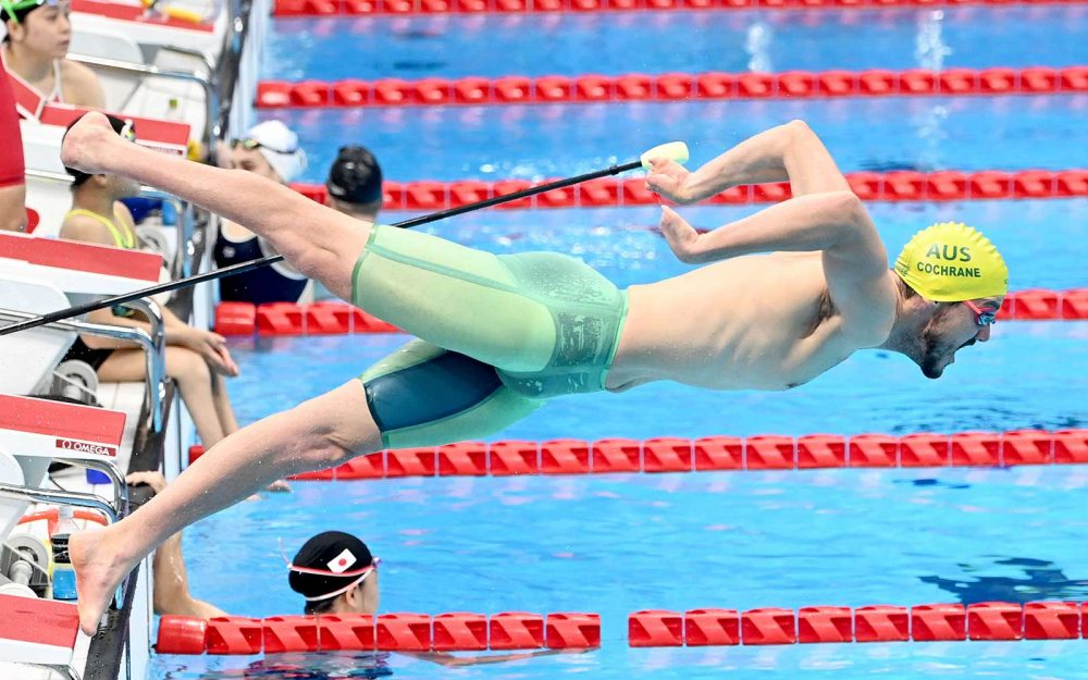 A male swimmer dives off the blocks into the pool