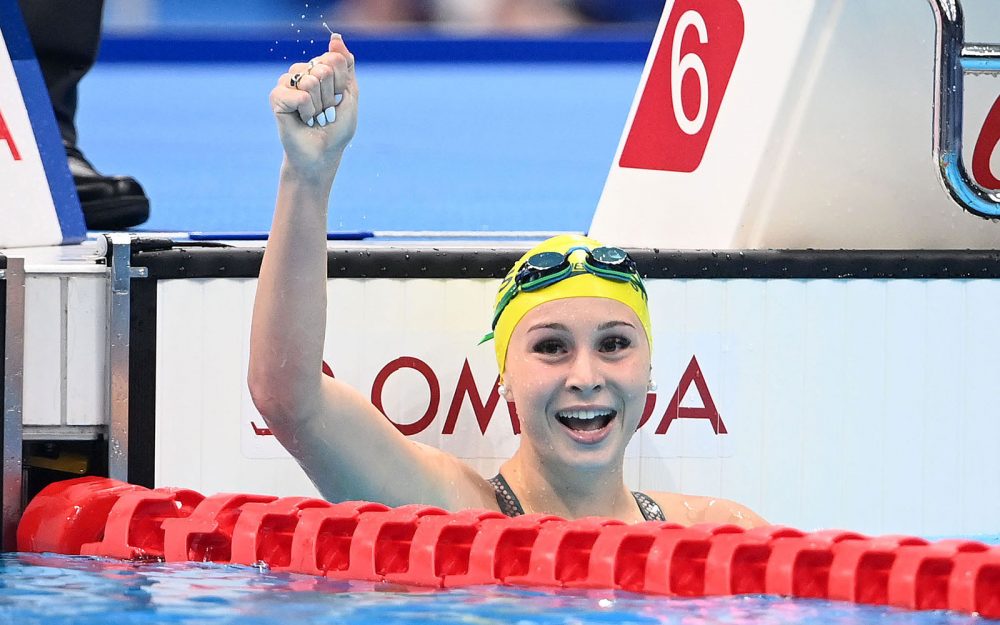 Female swimmer has just finished a race and is celebrating with her right arm raised above head.