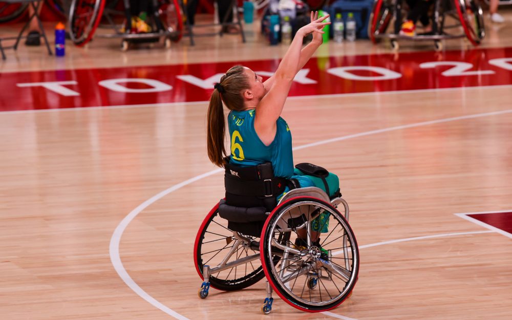 Female Australian Paralympian Hannah Dodd sitting in a wheelchair and shooting a basketball.