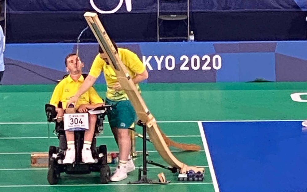 A male boccia player and ramp assistant during a boccia competition