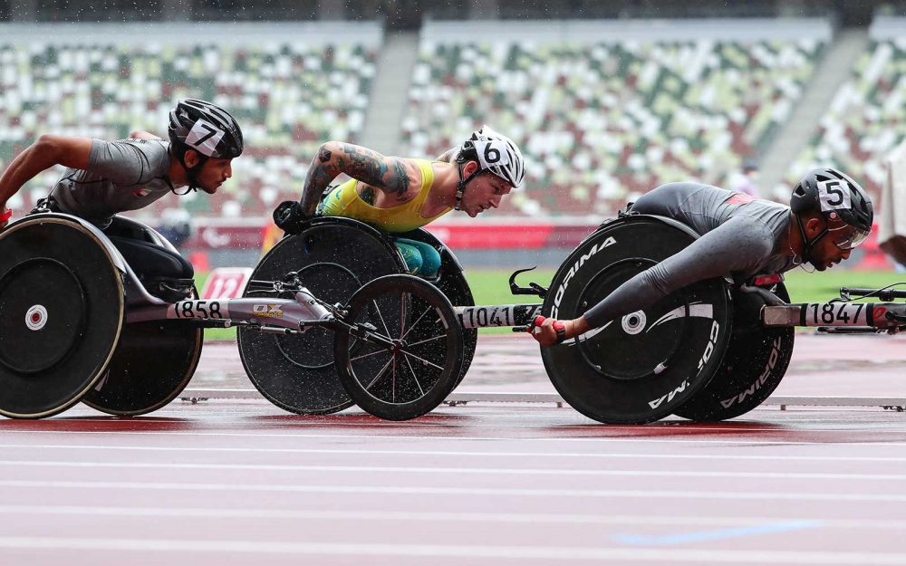3 male wheelchair racers from different countries on the track in a race
