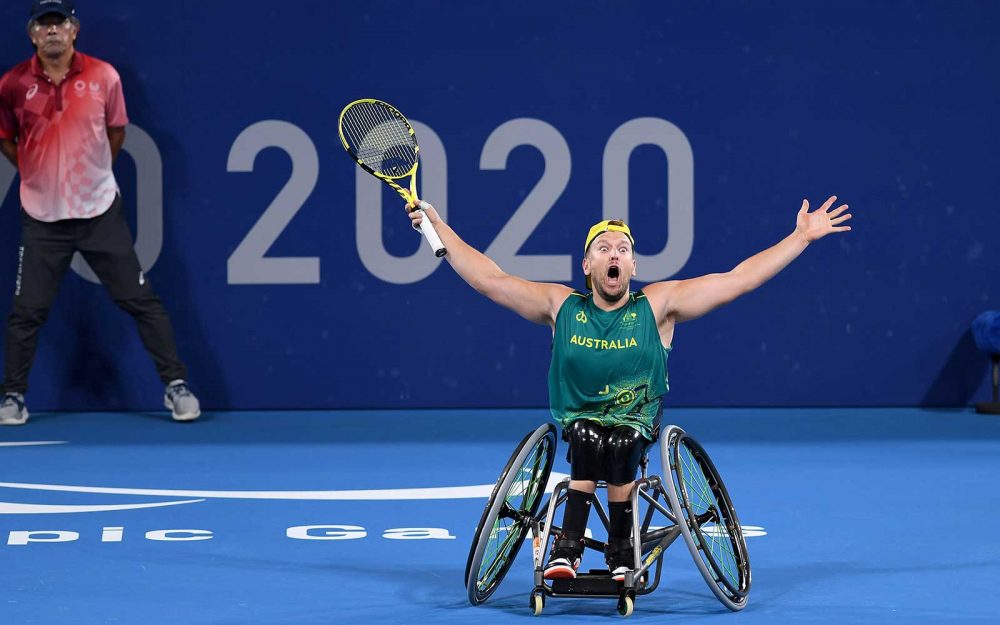 Australian wheelchair tennis player Dylan Alcott reacts to winning gold at Tokyo 2020 Paralympic Games with his arms outstretches above his head.