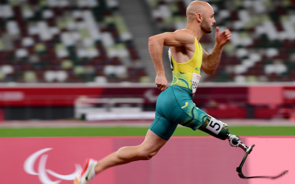 A male Australian Para-athletics athlete racing in Tokyo.