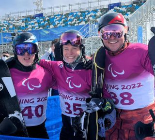 3 male snowboarders in a group smiling at the camera