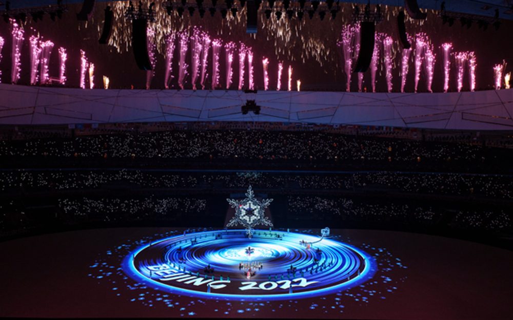 The Beijing 2022 Closing Ceremony. The flame lit in the middle of the Birdsnest stadium and fireworks in the background.