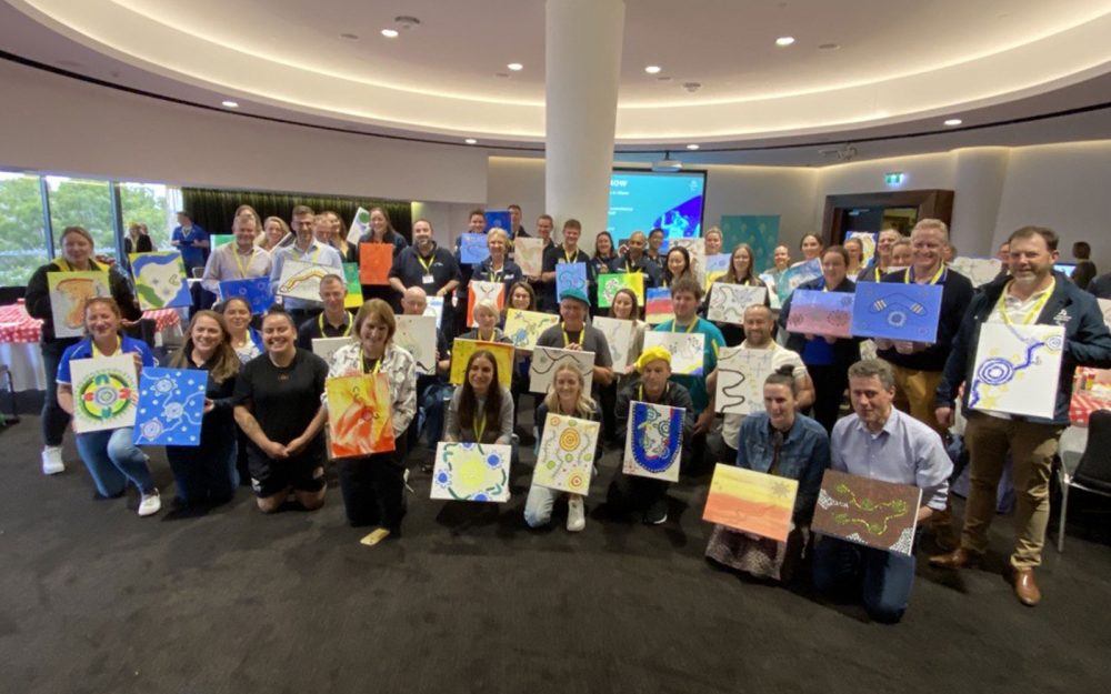 A group of people gathered for a photo. They are holding artworks.