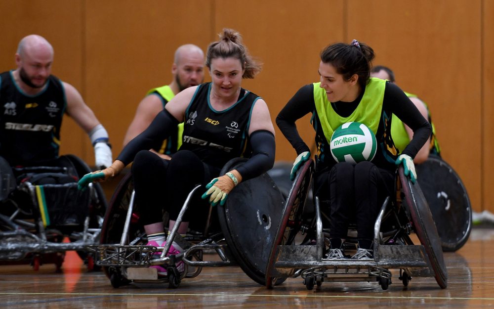Shae Graham and Ella Sabljak training for Wheelchair rugby. The ball is in Ella's lap.