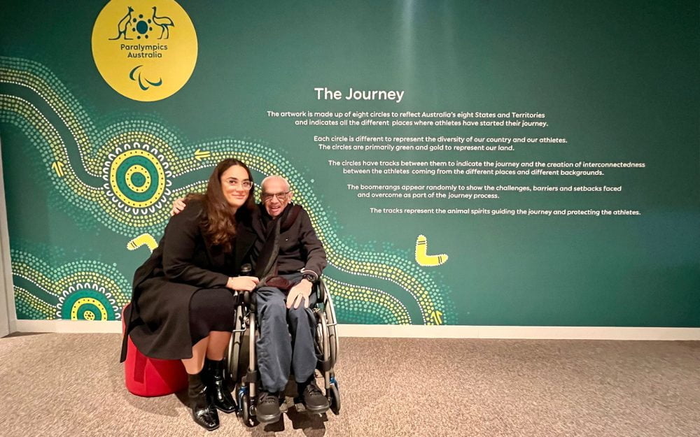 Australian Paralympian Kevin Coombs with Paralympics Australia RAP Coordinator Grace Sarra. Behind them is the story of 'The Journey'.