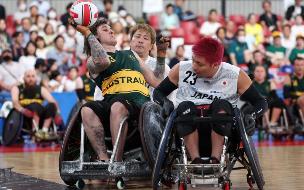 Australian Steelers wheelchair rugby player looks to pass the ball while under defence from Japanese opponents