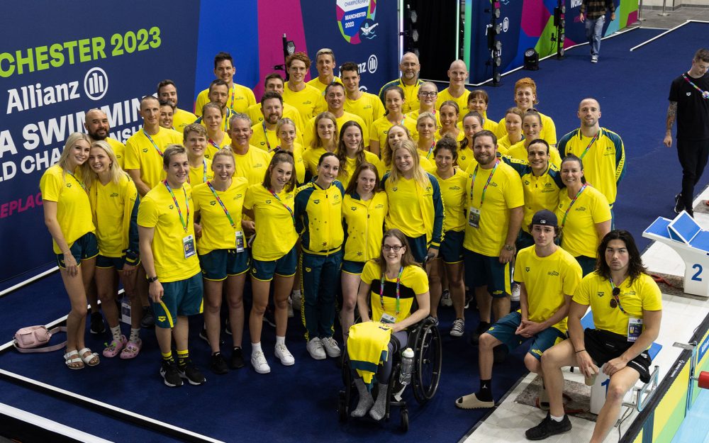 The Australian Dolphins Swim team for the 2023 World Para Swimming Championships huddled together smiling for a photo. They are all wearing yellow.