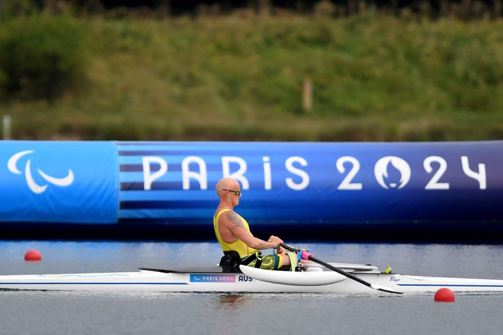 Para-rower Erik Horrie racing in front of a sign that reads Paris 2024.