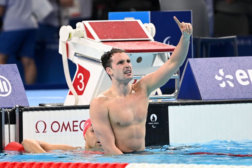 Ben Hance at the end of the pool pointing to the sky after breaking the men’s 100m backstroke S14 world record.