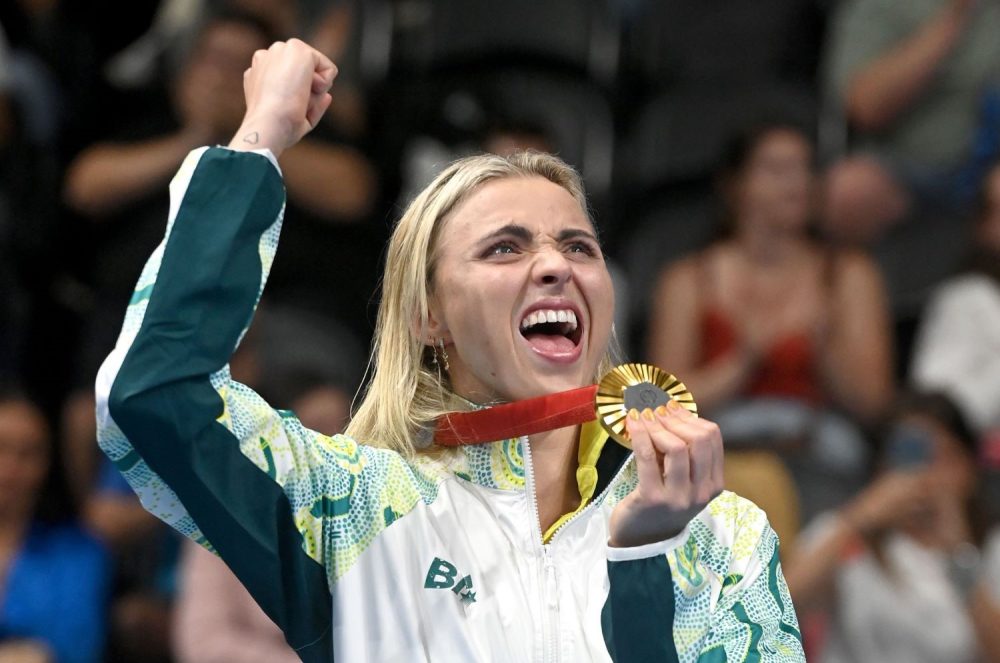 Para-swimmer Alexa Leary fist pumps and grasps the gold medal around her neck.