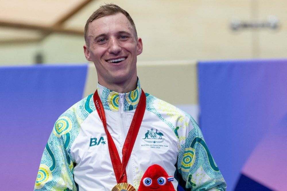 Para-cyclist Korey Boddington celebrating his gold medal on the podium at the Paris 2024 Paralympic Games.