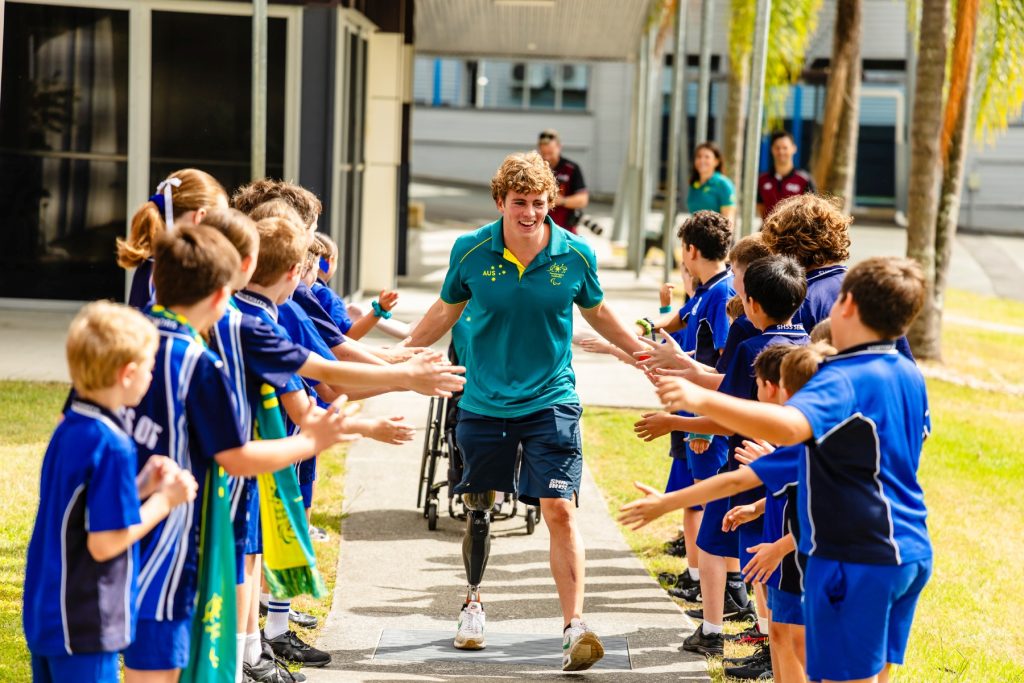 Lewis Bishop walking between a row of school children giving high fives